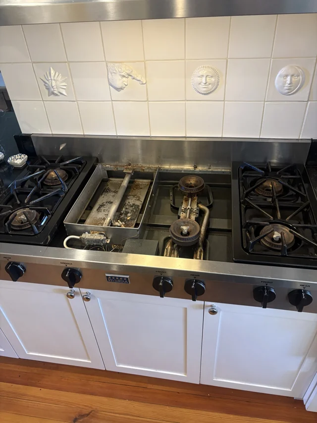 Cooking appliance opened during repair, showing internal burner components