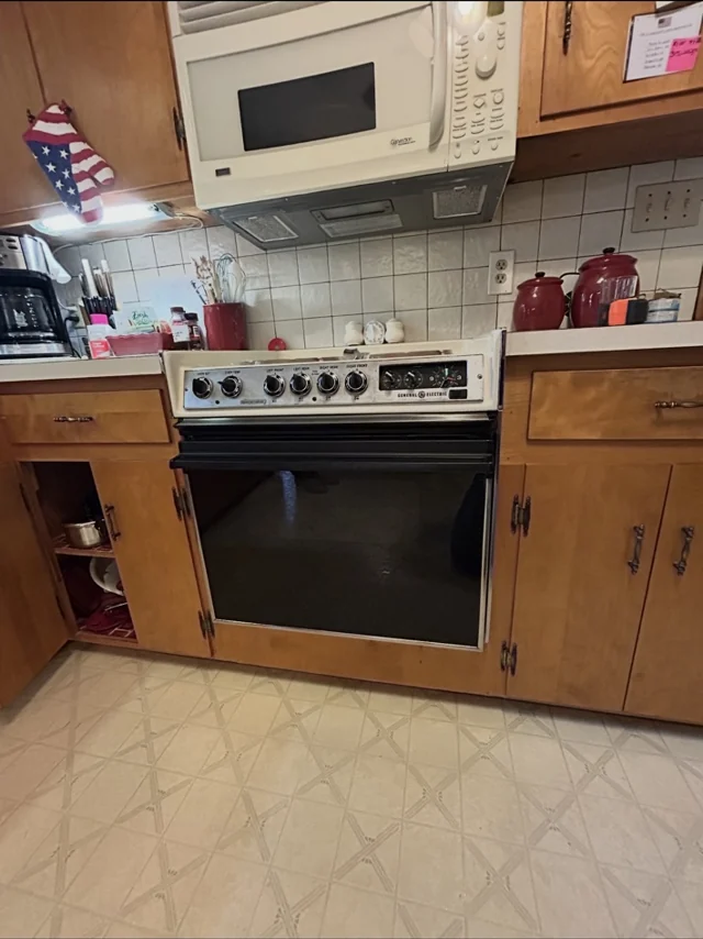 Before: older white microwave and black cooking appliance in oak cabinets